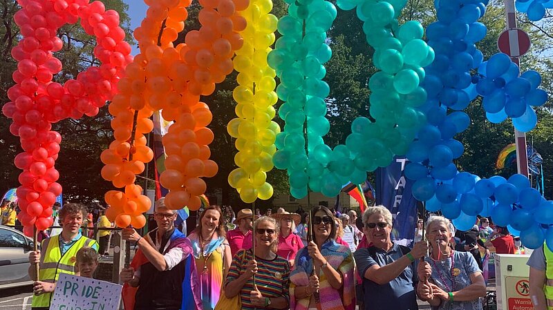 Surrey Lib Dems holding balloons spelling Pride