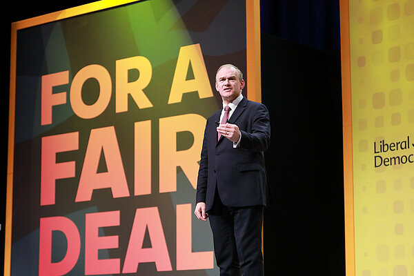 Ed Davey MP in front of Fair Deal signage