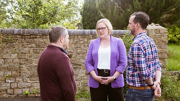 Zoe talks to a couple of supporters, they are stood outside in front of a wall
