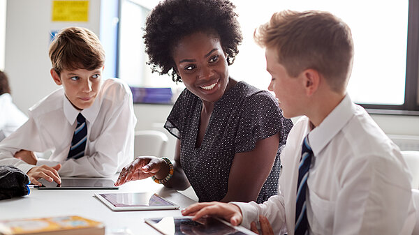 A teacher and two secondary school children using iPads.